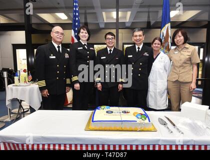 CORPUS CHRISTI, Texas (March 15, 2019) – Naval Health Clinic Corpus Christi Navy Medical Corps doctors celebrate the 148th Birthday of their Corps.  From left: Capt. Miguel A. Cubano, commanding officer, Cmdr. April L. Breeden, Lt. Thong X. Tran, Lt. Cmdr. Lawrence A. Ramirez, Retired Lt. Cmdr. Monique E. Smith and Lt. Cmdr. Di Khoo.  With over 3,700 Navy Physicians on active duty and 500 in the reserves, the Corps is an unmatched medical force, ready to support any operational requirement that develops during an uncertain future. The call to preparedness extends well beyond the challenges of  Stock Photo