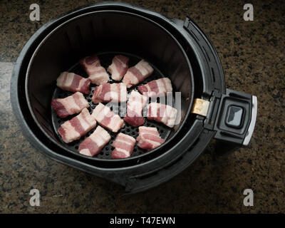 Pork Belly cooking in an air fryer basket Stock Photo
