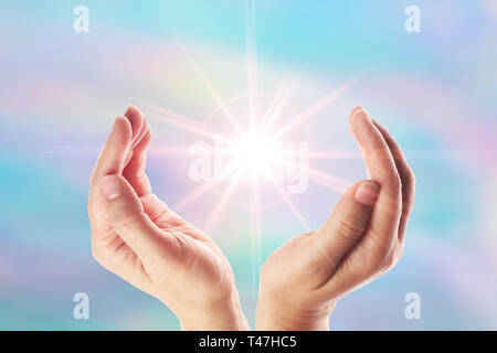 Healing hands with bright sunburst on rainbow background Stock Photo