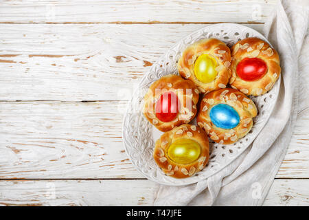 Traditional Easter buns decorated with eggs, almond petals and lemon zest. Sweet festive bread in the form of bird nests. Selective focus. copy space  Stock Photo