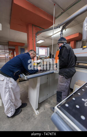two young carpenters calculating and programming a cnc wood working machine in workshop. wood workers preparing a computer program for CNC machine at  Stock Photo