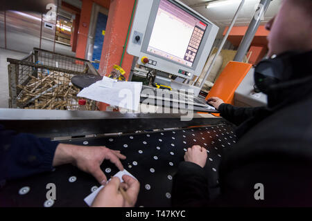 two young carpenters calculating and programming a cnc wood working machine in workshop. wood workers preparing a computer program for CNC machine at  Stock Photo