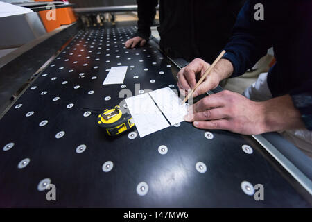 two young carpenters calculating and programming a cnc wood working machine in workshop. wood workers preparing a computer program for CNC machine at  Stock Photo