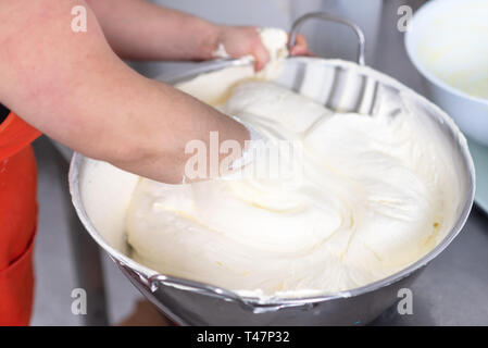 Mixing white egg cream in bowl with hands, baking cake . Stock Photo