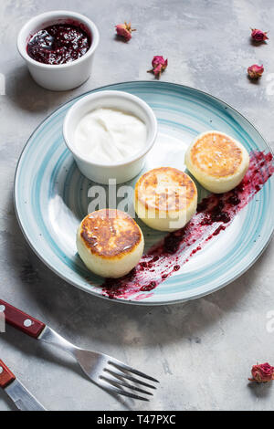 Cottage cheese pancakes on concrete background. Syrniki with jam. Homemade food Stock Photo