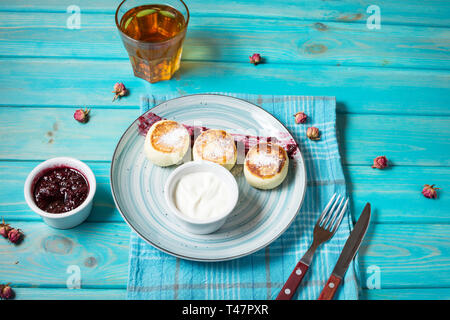 Cottage cheese pancakes on blue wooden background. Syrniki with jam. Homemade food Stock Photo