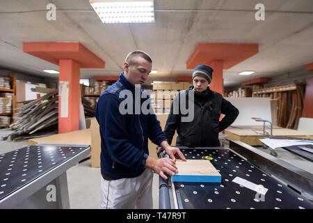two young carpenters calculating and programming a cnc wood working machine in workshop. wood workers preparing a computer program for CNC machine at  Stock Photo