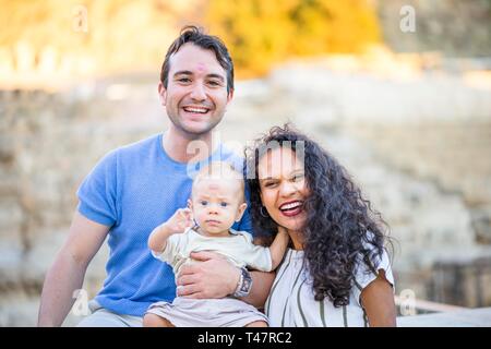 Young happy couple enjoying time with small baby boy, father and son with lipstick prints on their foreheads, Poland Stock Photo