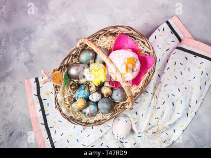 Basket with easter cakes and painted eggs on concrete background. Easter concept. Top view Stock Photo