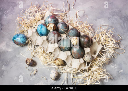 Quail and chicken painted eggs on concrete background. Easter decorations. Stock Photo