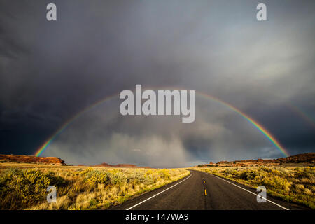 A full rainbow and thuderstorm clouds over Scenic Highway 211 in Canyonlands National Park, Southeast Utah, USA. Stock Photo