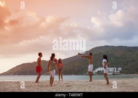 Group of young people playing volleyball on beach at sunset Stock Photo