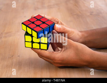 Rubik cube intelligence toy solving in a hand, in a wood table Stock Photo