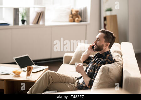 Talking by phone on couch Stock Photo