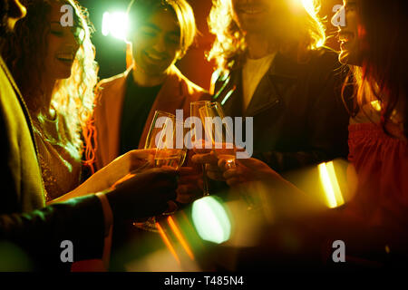 Clinking flutes together in nightclub Stock Photo