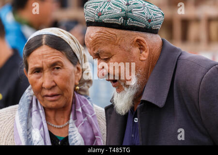 Portrait of elderly Uyghur couple having a conversation at Kashgar Animal Market (Xinjiang Province, China) Stock Photo