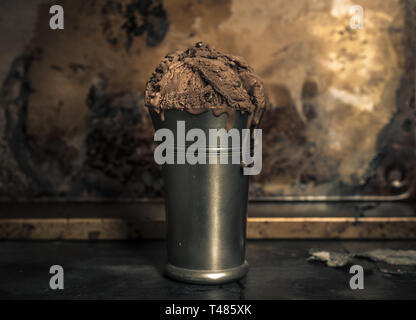 chocolate ice cream in an old metal mug on a dark metal gloss background Stock Photo