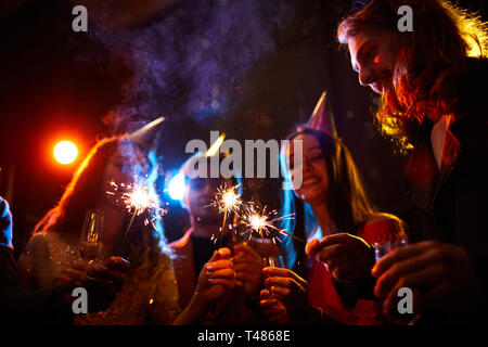 Friends lighting sparklers at birthday party Stock Photo