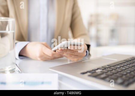 Woman using mobile phone at workplace Stock Photo