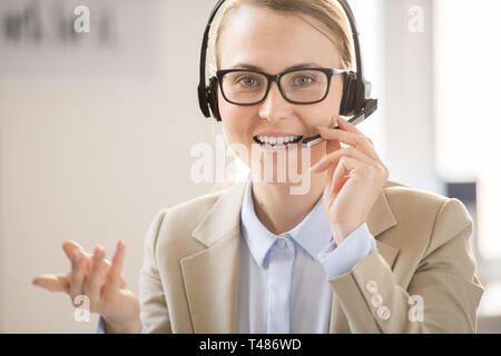 Confident helpline operator talking via headset with microphone Stock Photo