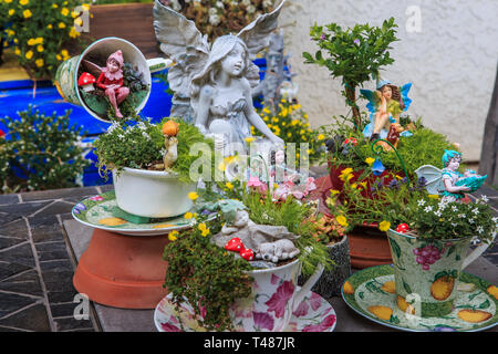 Miniature table top fairy garden with teapots and teacups used as flower pots with fairytale themes and miniature figurines . Stock Photo