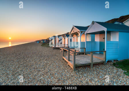 Beautiful sunset over a row of colourful beach huts at Milford on Sea on the Hampshire coast Stock Photo