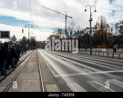 Vienna, Austria, 23 February 2019. People waiting at a tram stop on an empty street on the ring in the afternoon sun on a winter's day Stock Photo