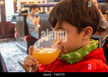 A young boy drinks fruit shoot in a pub from a large goblet style glass Stock Photo