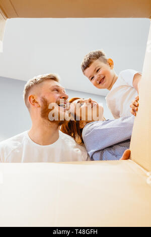 Happy family just moved in new house and looking at box, unpacking boxes with belongings, moving concept Stock Photo