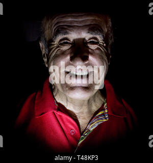 Portrait of smiling old caucasian man. Low-key lighting. Isolated on black. Stock Photo