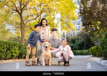 Happy young family playing with dog Stock Photo