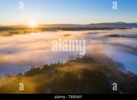 Sunrise over woods and meadows with morning fog in winter, at the back Alpine chain, near Geretsried, Tolzer Land, drone shot, Alpine foothills Stock Photo