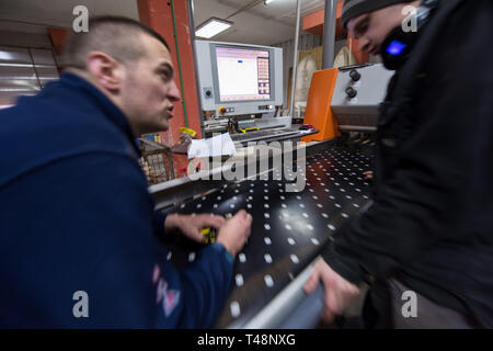two young carpenters calculating and programming a cnc wood working machine in workshop. wood workers preparing a computer program for CNC machine at  Stock Photo
