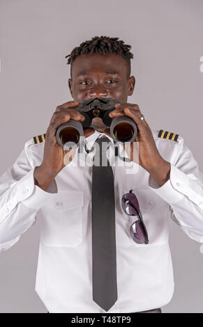 London UK, April 2019.  Young airline pilot using a pair of binoculars. Stock Photo