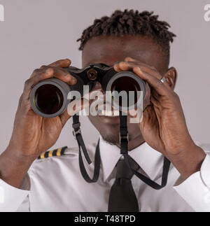 London UK, April 2019.  Young airline pilot using a pair of binoculars with focus on hands and lenses. Stock Photo