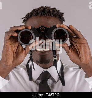 London UK, April 2019.  Young airline pilot using a pair of binoculars with focus on hands and lenses. Stock Photo