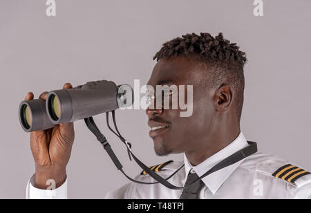 London UK, April 2019.  Young airline pilot using a pair of binoculars. Stock Photo