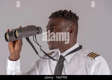 London UK, April 2019.  Young airline pilot using a pair of binoculars. Stock Photo