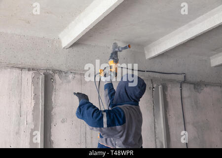 Worker builder makes electrical wiring, bites with tongs a black ...