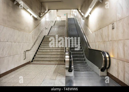 April 14, 2019. Greece, Athens. Empty electric escalators and stairway at a metro station in the city center. Marble tiled wall and floor, stainless s Stock Photo