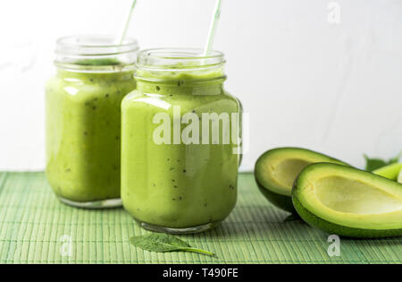 Green smoothie in glass on green background made by avocado, lemon and kiwi. Stock Photo