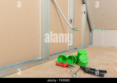 Electricity wire installation into plasterboard wall in attic. Attic renovation Stock Photo
