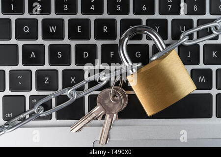 Padlock with chain and keys on a laptop computer keyboard. Cyber security abstract concept. Stock Photo