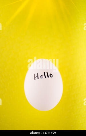 White chicken egg with black inscription hello on a yellow background Stock Photo