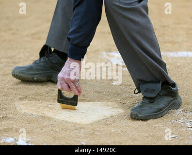 Umpire cleaning home plate at a baseball game Stock Photo