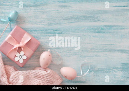Easter flat lay in pastel colors with copy-space. Wrapped gift box, decorative flowers and Easter eggs. Stock Photo