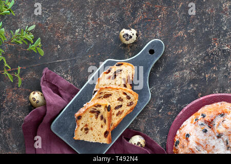 Easter Bread (Osterbrot in German). Top view of traditional fruty bread on dark table with fresh leaves and quail eggs. Traditional German dessert for Stock Photo