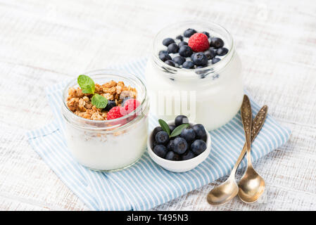 Greek yogurt with berries and granola cereals in jar on blue checkered napkin. Food for dieting, weight loss, healthy lifestyle, healthy breakfast or  Stock Photo