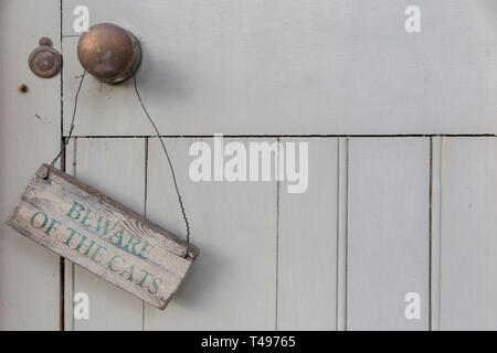 A sign warning to 'Beware of the Cats' on a weathered outside door Stock Photo