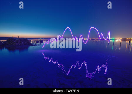 Amazing laser fireshow performance in the night blue sky with reflections in the sea water Stock Photo